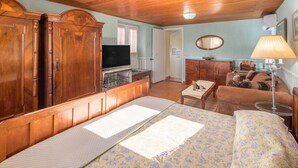 A bedroom with a wooden wardrobe, a television, a desk, a bed with floral bedding, a mirror, and a lamp. - Lovely home in Ravni with WiFi (Ravni)