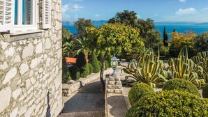 A stone building with a view of the sea and a garden with various plants. - Lovely home in Ravni with WiFi (Ravni)