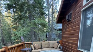 Eine Holzterrasse mit Korbmöbeln und einem Steintisch für ein Feuer.