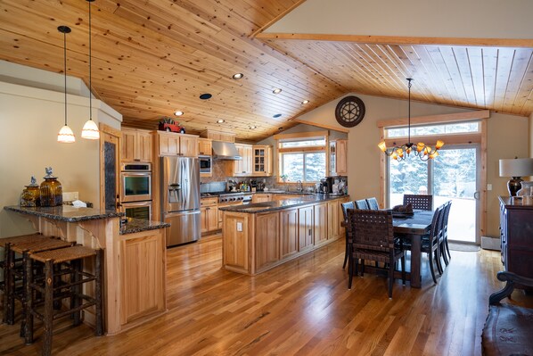 Une cuisine spacieuse avec des meubles en bois, un grand îlot central et un coin repas équipé de chaises.