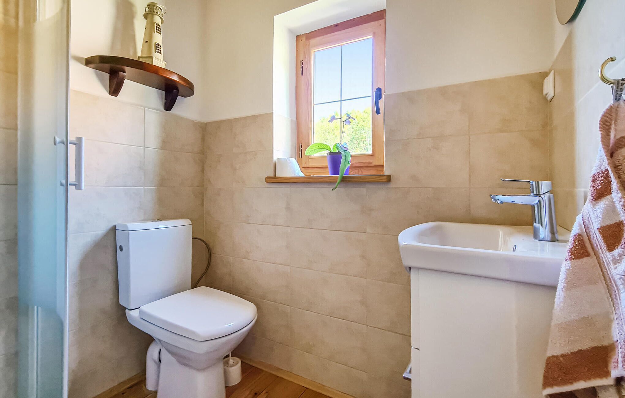 Un baño con inodoro, lavamanos y ventana con planta.