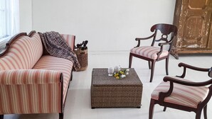 Una sala de estar con un sofá a rayas, una mesa de centro de mimbre y dos sillones.