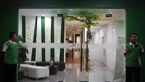 A modern interior with a reception desk, seating area, and a glass wall with a decorative tree.