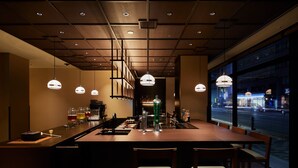 A modern bar area with a long counter, bar stools, and pendant lighting. - Agora Kyoto Shijo (Kyoto)