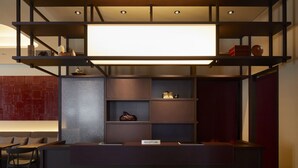 A reception desk with a sign labeled "RECEPTION," a seating area with chairs, and a wall with a red brick pattern. - Agora Kyoto Shijo (Kyoto)