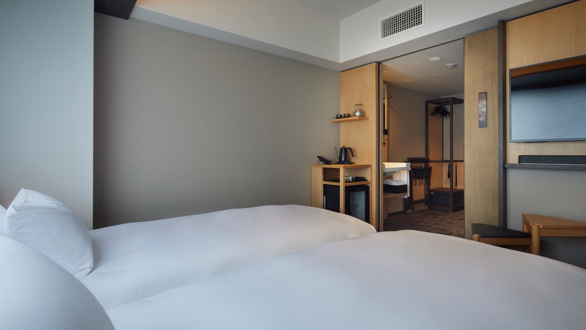 Una camera d'albergo con un letto grande, una scrivania con un bollitore e una televisione.