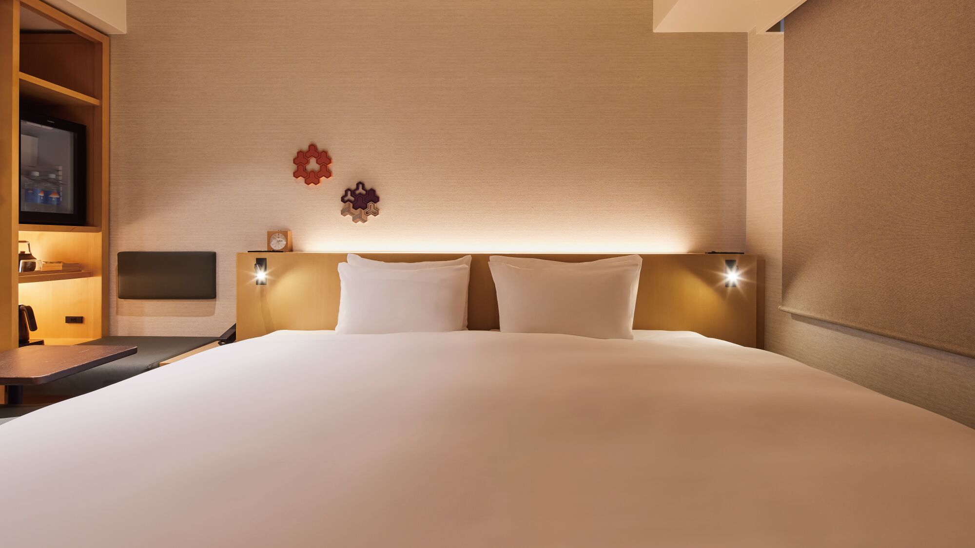 Ett hotellrum med en stor säng, sängbord, en tv och väggmonterade lampor.