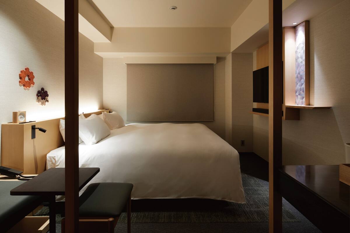 Een hotelkamer met een groot bed, een bureau met stoel, een televisie en een klein tafeltje.
