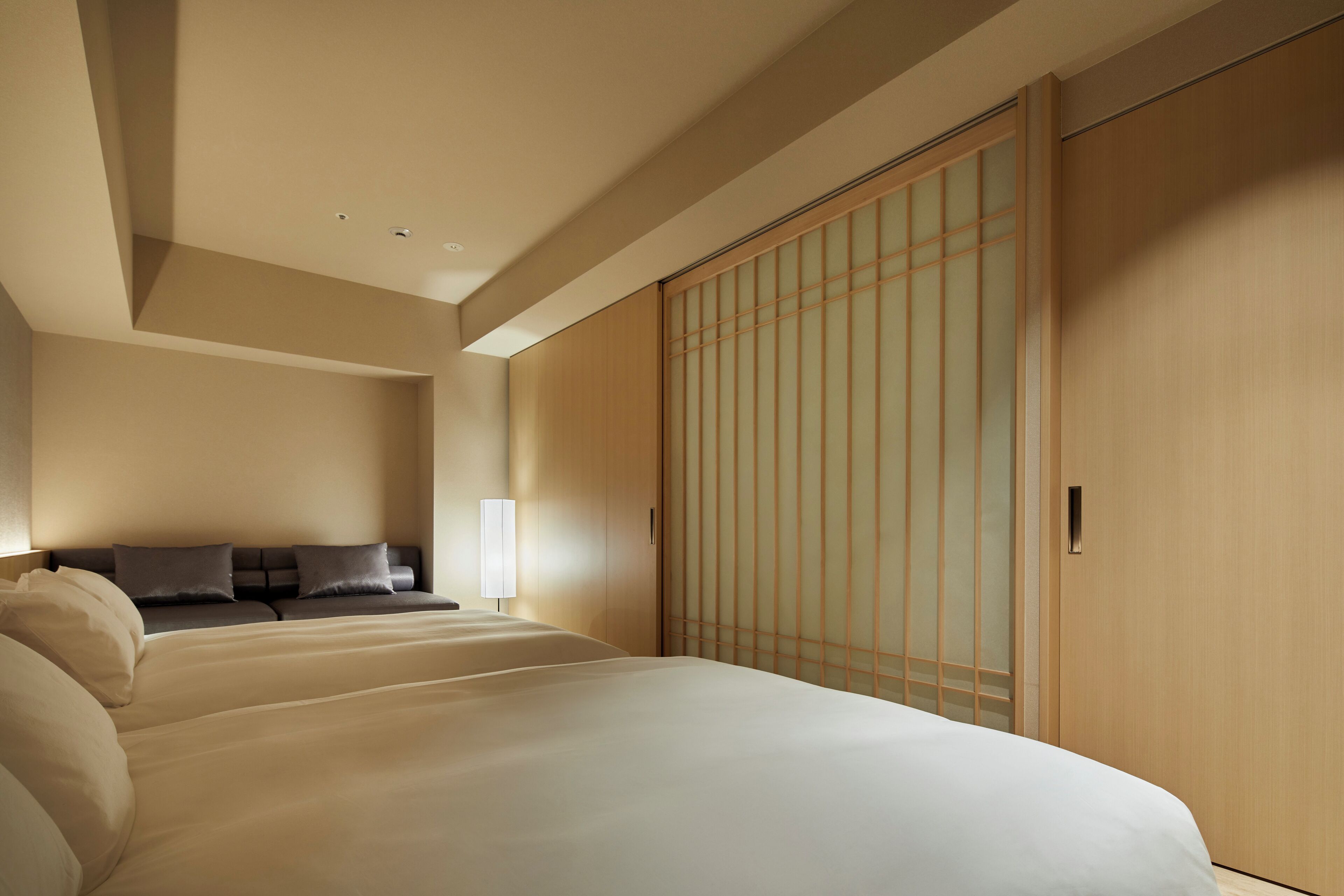Habitación de hotel con una cama grande, un sofá y una puerta corredera de madera.