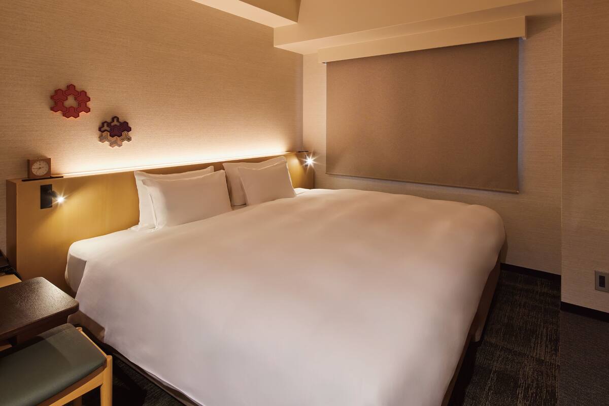 Een hotelkamer met een groot bed, een bureau met stoel en een klok aan de muur.