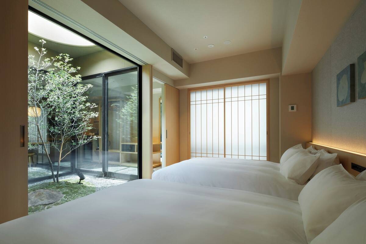 Een moderne hotelkamer met een groot bed, schuiframen naar een tuin en een traditionele shoji-scherm.