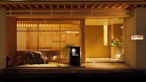 Une entrée de style japonais traditionnel, avec une porte en bois, un rocher et une pancarte.