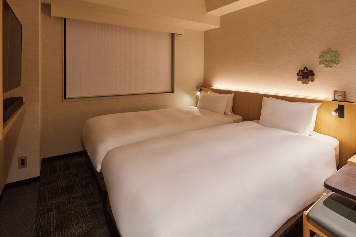 Een hotelkamer met twee bedden, een televisie en een tafeltje.