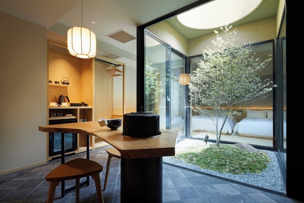 A modern kitchen with a dining area, a large window, and a small garden.