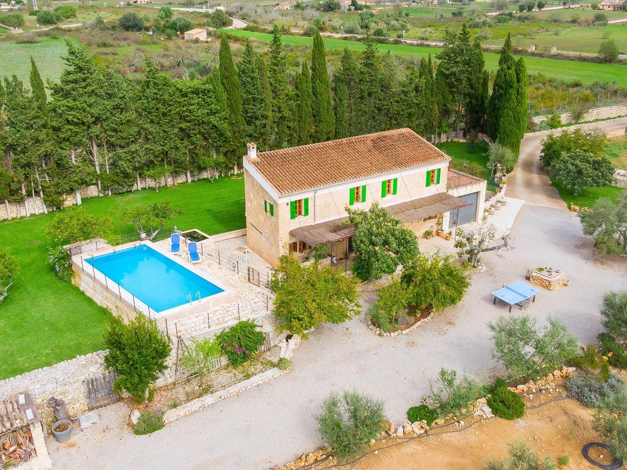Une villa avec piscine, des volets verts et une façade en pierre.