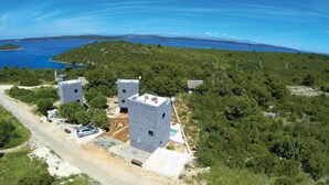 A coastal property with two stone towers, a swimming pool, and a road leading to the property.