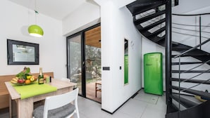 A modern kitchen with a wooden table, a green chair, and a green door.