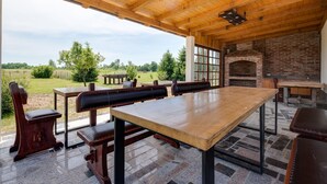 Un área de comedor al aire libre con horno de ladrillo, mesas y sillas de madera.