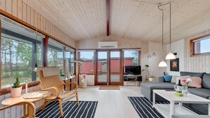 Un intérieur de chalet moderne comprenant un coin repas, un canapé et un téléviseur.
