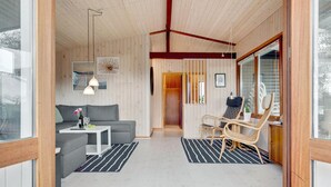 Un intérieur moderne avec un canapé gris, une petite table blanche, une chaise en osier et un bureau en bois avec une chaise.