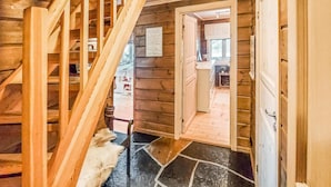 Eine Holztreppe führt zu einem Raum mit Steinboden und einer Tür, die in einen weiteren Raum öffnet.