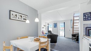 A modern kitchen with a white table and chairs, a coffee machine, and a view of the outside.