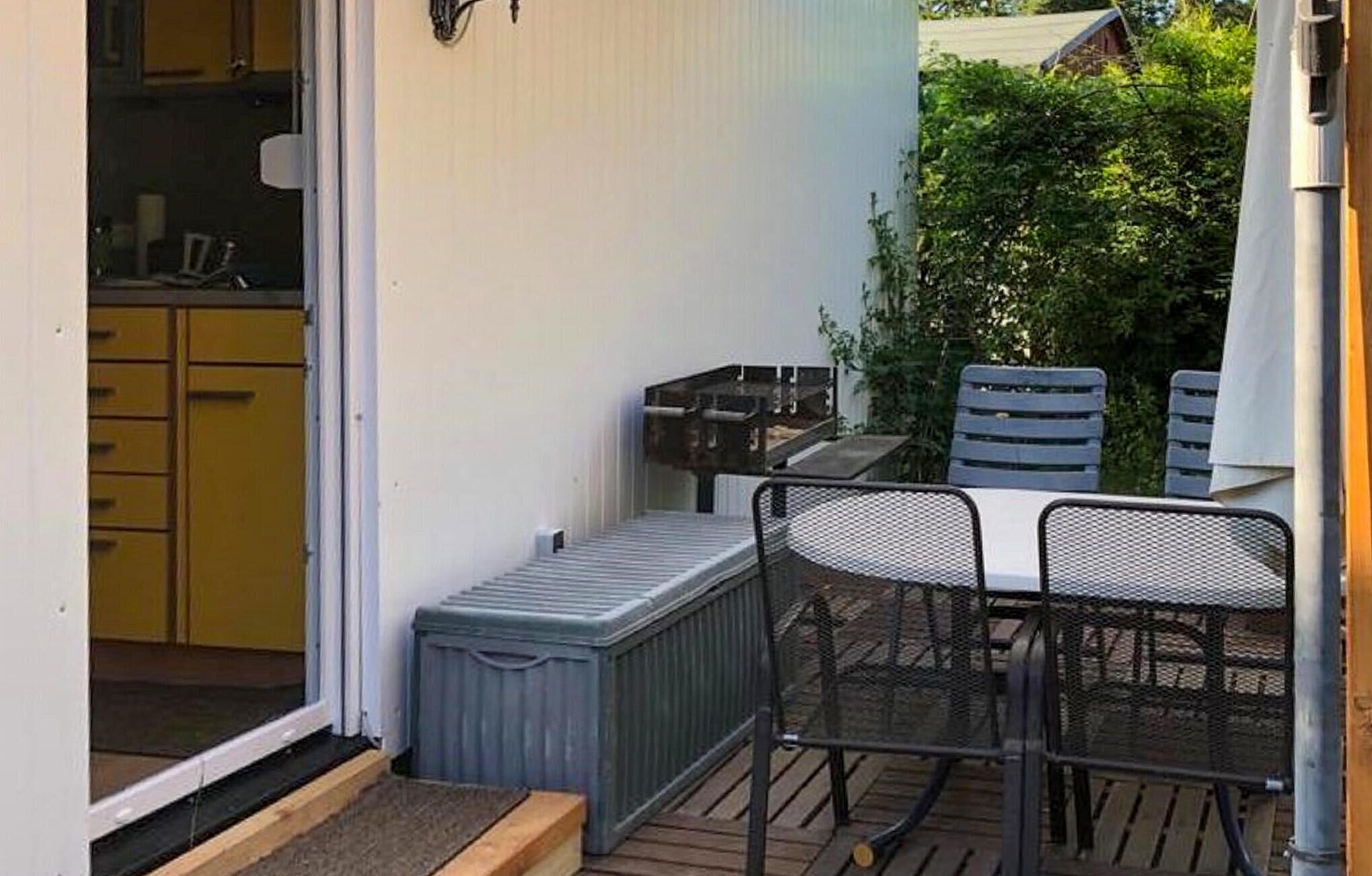 A patio with a metal table and chairs, a small grill, and a shed.
