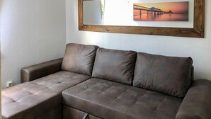 A sectional sofa with a wooden frame and a picture of a bridge on the wall. - 1 bedroom lovely home in Ueckermuende (Ueckermuende)