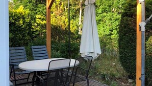 An outdoor patio with a round table and chairs, surrounded by greenery. - 1 bedroom lovely home in Ueckermuende (Ueckermuende)