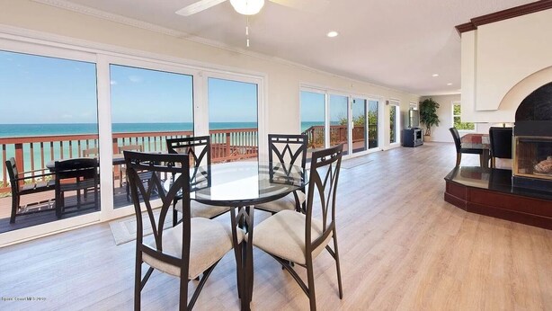 Un balcon spacieux avec vue sur l’océan, un coin repas avec une table et des chaises en verre, et une cheminée.