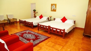 A room with two wooden beds, a red sofa, a patterned rug, and a painting on the wall.
