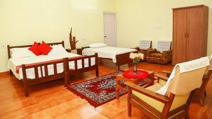 A room with two wooden beds, a wooden wardrobe, a chair, and a small table with a vase of flowers. - Deluxe Double Room In British Bungalow (Vythiri)