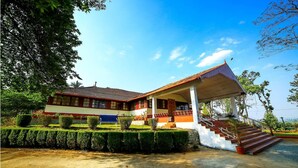A two-story building with a tiled roof and a covered porch. - Deluxe Double Room In British Bungalow (Vythiri)