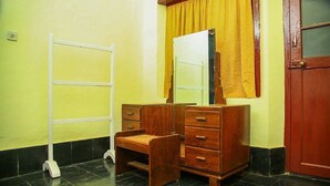 A room with a wooden dresser, a mirror, a yellow curtain, a white ladder, and a red door. - Bungalow With Tea Garden View (Vythiri)