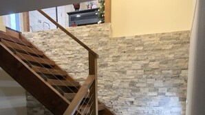 A wooden staircase with a stone wall background. - Golf Course Villa (East Wenatchee)