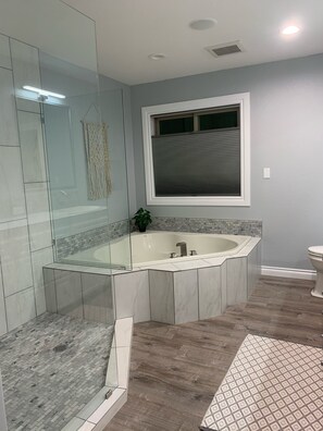 A modern bathroom with a glass-enclosed shower, a freestanding bathtub, and a toilet. - Golf Course Villa (East Wenatchee)