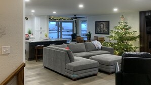A modern living room with a grey sectional sofa, a black armchair, and a wooden staircase. - Golf Course Villa (East Wenatchee)