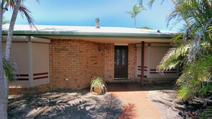A single-story brick house with a flat roof, a front door, and a small porch area. - 36 Trevors Road Bargara (Bargara)