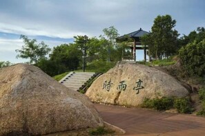 A pavilion with a roof, surrounded by large rocks with inscriptions, and a staircase leading up to it. - Bafaimile Hotel (Shiyan Hongfa World Branch) (Shenzhen)