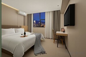 A hotel room with a bed, a desk, a chair, a TV, and a window with a city view. - Bafaimile Hotel (Shiyan Hongfa World Branch) (Shenzhen)