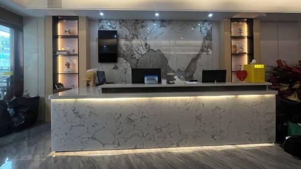 A reception desk with a marble finish, a flat-screen TV, and a digital display. - Bafaimile Hotel (Shiyan Hongfa World Branch) (Shenzhen)