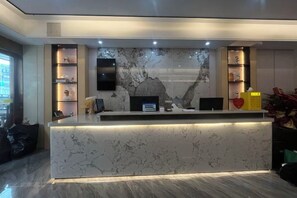 A reception desk with a marble top, a flat-screen TV, and a digital display. - Bafaimile Hotel (Shiyan Hongfa World Branch) (Shenzhen)
