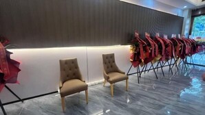A hotel lobby with a row of beige chairs, a dark textured wall, and a tiled floor. - Bafaimile Hotel (Shiyan Hongfa World Branch) (Shenzhen)