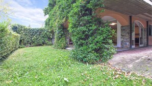 Un jardin luxuriant, avec un mur en pierre et l’entrée d’un bâtiment.
