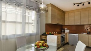 Una cocina moderna con armarios de madera, una mesa de comedor de vidrio y un frutero.