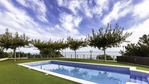 Una piscina rectangular con superficie de agua azul cristalina, rodeada de césped artificial bien cuidado.