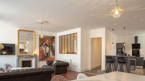 A modern living room with a marble coffee table, leather sofas, a large painting, and a dining area with bar stools. - Suite Napoléon III - 6.pers - downtown Charleville-Mézières (Charleville-Mézières)