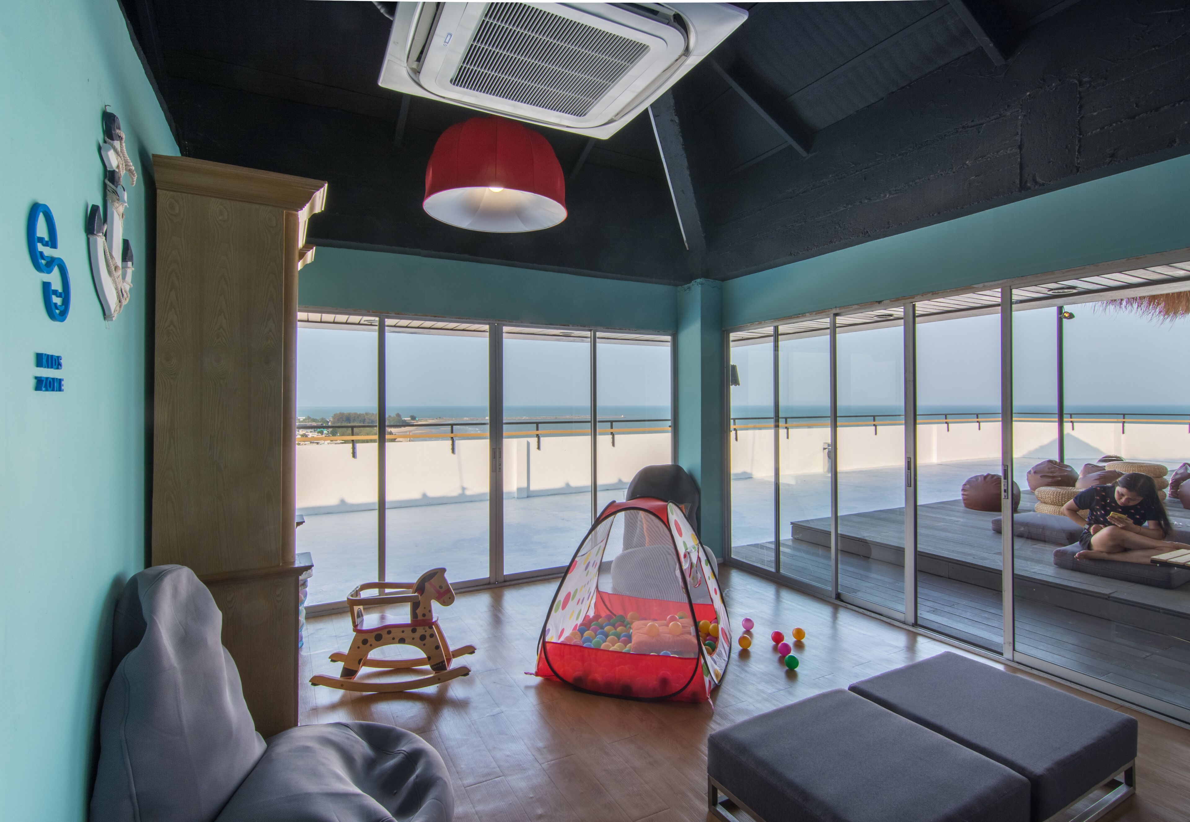 Una stanza con vista sulla spiaggia, una poltrona a dondolo, una tenda da gioco e una panca.