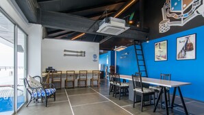 A modern dining area with high tables and chairs, a bar counter, and a blue accent wall.