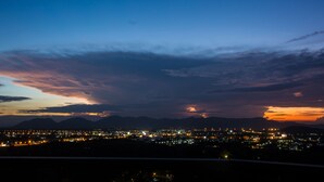 A cityscape at dusk with a view of mountains in the background.